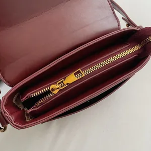 Draufsicht der weinroten Vintage-Umhängetasche mit mehreren Innenfächern und Goldzipper