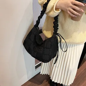 Detailed shot of black quilted hobo bag with ruffled strap and side drawstring accents