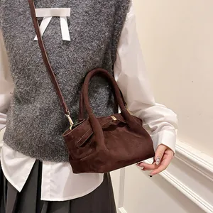 Detail of dark brown faux suede tote bag featuring matte texture and golden hardware accents