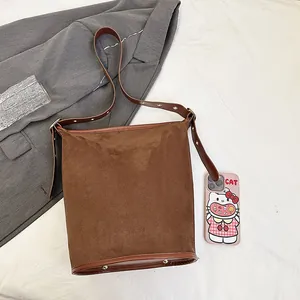 Detailed close-up of dark brown suede bucket bag with adjustable metal buckle strap