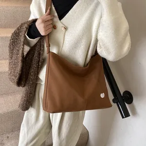 Brown tote bag on model showing large capacity and adjustable shoulder strap detail
