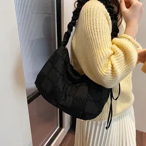 Detail view of black quilted nylon bag featuring stylish ruffled shoulder strap design