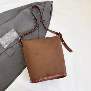 Detailed view of the brown suede bucket bag featuring adjustable metal buckle and rivets