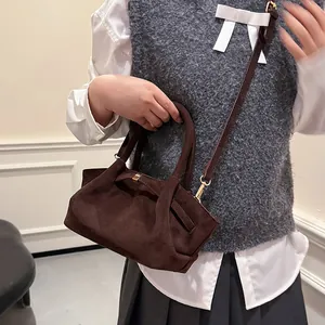 Detail of dark brown faux suede tote bag with golden metal hardware and adjustable strap