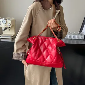 Detail of red quilted bucket bag with gold chain strap and drawstring closure