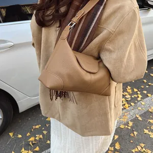 Détail du sac sous l'aisselle en cuir marron caramel avec des boucles en métal argenté