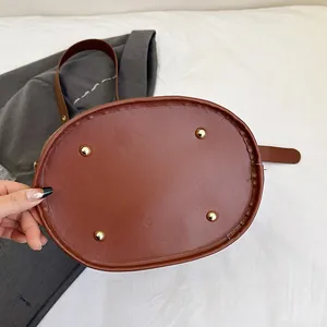 Close-up of the bucket bag's oval base featuring four protective golden metal feet