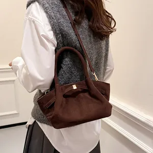 Detail of dark brown suede tote bag featuring a gold buckle and textured vintage fabric