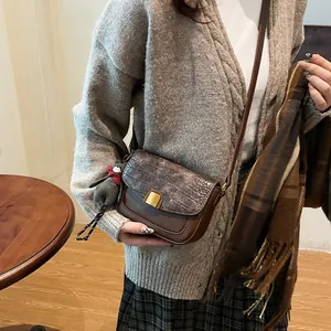 Detail der braunen Retro-Umhängetasche mit Krokoprägung, Katzenanhänger und Goldschnalle