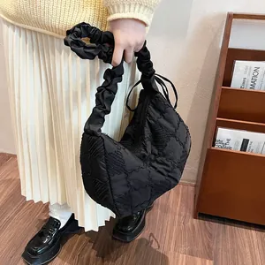 Detail of black quilted dumpling bag with ruched cloud handle in warm lifestyle setting
