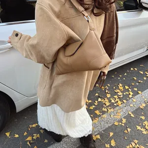 Détail d'un sac à bandoulière en cuir marron à motif litchi sur un mannequin en automne