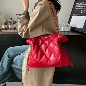 Detail of red quilted chain bag showing glossy texture and elegant drawstring closure