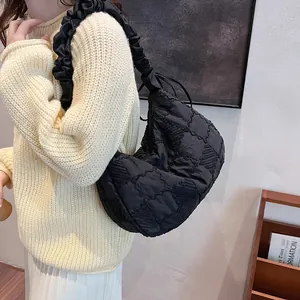 Detail of black quilted shoulder bag featuring unique ruffled strap and padded texture