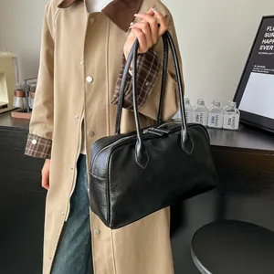 Detailed view of black litchi pattern leather tote bag styled with a khaki trench coat