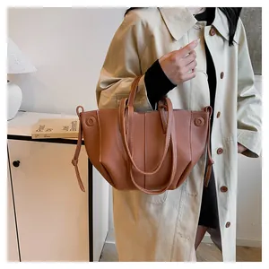 Détail du sac cabas en cuir grainé marron avec coutures décoratives et cordons de serrage
