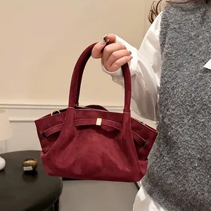 Detail of burgundy suede tote bag featuring a decorative bow-shaped buckle and side pleats