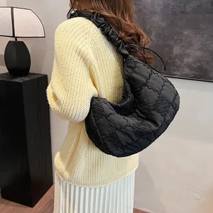 Detailed view of black quilted dumpling bag with stylish ruffled shoulder strap on model