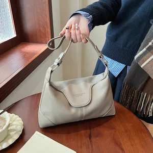 Détail du sac beige en cuir grainé avec texte embossé et boucles en métal argenté