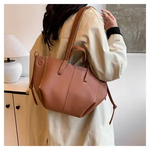 Détail du cabas en cuir marron avec motif litchi et détails de cordons latéraux