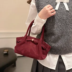 Detail of burgundy suede tote bag featuring a metallic bow buckle and matte texture