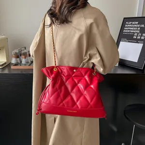 Macro detail of red quilted leather shoulder bag with gold chain and drawstring closure
