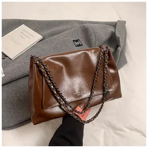 Detail of dark brown oil wax leather shoulder bag with silver logo and chain strap