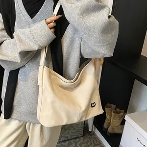 Detailed macro of cream faux leather tote bag showing fine texture and metal emblem