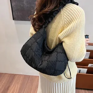 Detail of black quilted shoulder bag featuring ruffled straps and large lattice texture