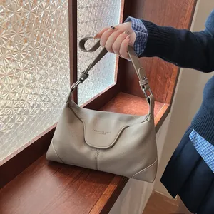 Détail du sac à bandoulière en cuir litchi grège avec boucle argentée et logo embossé