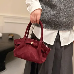 Detail of burgundy faux suede tote bag featuring elegant pleated texture and gold buckle