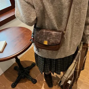 Detail der braunen Retro-Umhängetasche mit Kroko-Textur und goldener Metallschnalle