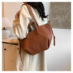 Sac cabas en cuir marron avec cordons latéraux porté par un mannequin dans un décor minimaliste