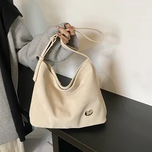 Macro detail of the cream-colored hobo bag featuring a small silver heart-shaped emblem