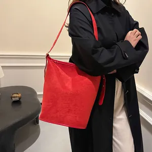 Fashionable red suede bucket bag for women styled as a shoulder bag over a long coat