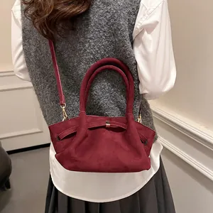 Detail of burgundy faux suede tote bag with metal buckle strap and top handle design