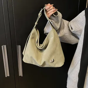 Detail of sage green suede hobo bag with a distinctive silver metallic bean-shaped buckle
