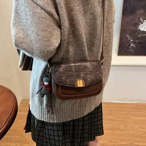 Details einer Vintage-Satteltasche in Dunkelbraun mit Kroko-Prägung und Goldverschluss