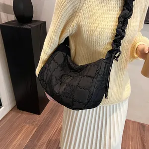 Macro detail of the black quilted crescent bag with a decorative ruffled shoulder strap