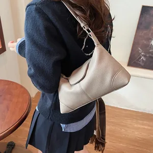 Détail d'un sac à bandoulière en cuir marron clair avec motif litchi et boucle en métal