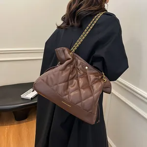 Detail of dark coffee quilted leather tote bag with chain strap and side drawstring