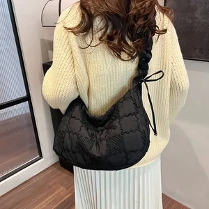 Detail of black quilted puffer bag with ruffled strap and side bow decoration