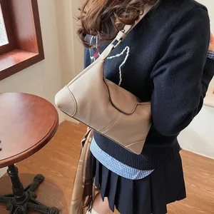 Détail du sac demi-lune en cuir grainé beige avec rabat magnétique et bandoulière
