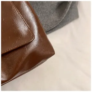 Detail of dark brown leather tote showing fine stitching on rounded corners and flap edge
