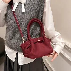 Detail of burgundy suede tote bag with metal buckle strap and crossbody strap shown on model