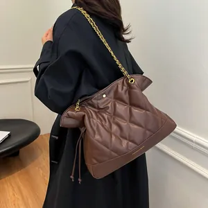 Macro detail of brown quilted leather bucket bag with golden chain strap on a model