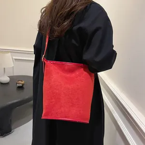Detail of red frosted suede bucket bag featuring adjustable strap and sleek gold hardware