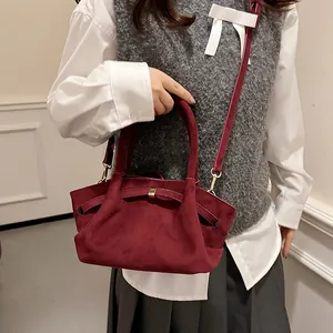Close-up of wine red faux suede tote bag with a bow detail and slender shoulder strap