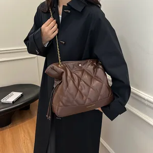 Detail of a brown quilted leather bucket bag with gold chain strap and drawstring accents