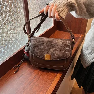Detailansicht braune Handtasche mit Krokostruktur, goldener Schnalle und Bärenanhänger