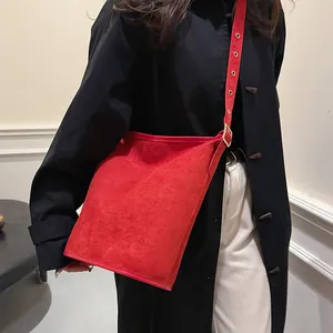Macro view of red frosted suede bucket bag featuring adjustable metal eyelet shoulder strap